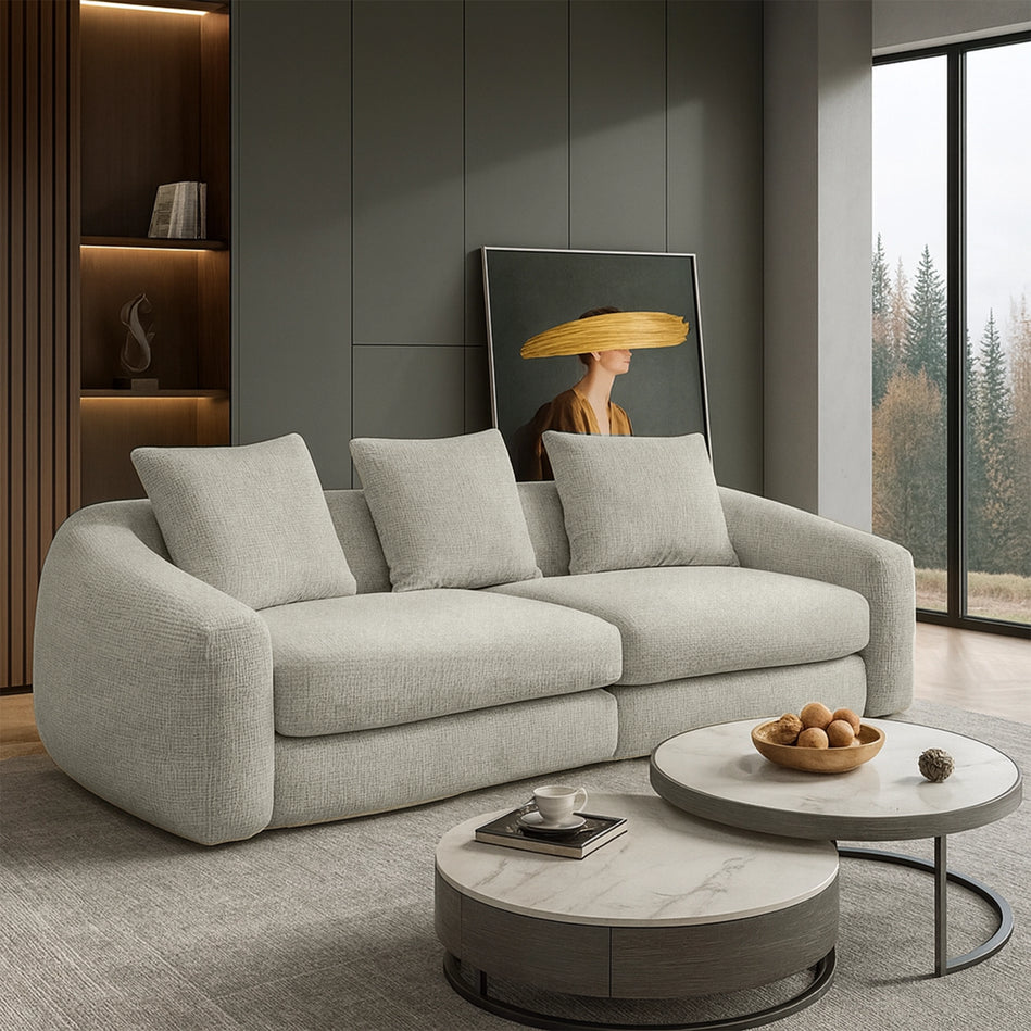 Modern living room with a gray sofa, round coffee tables, and a decorative wall piece.